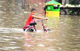 A boy drags his bicycle on a flooded Bathinda road on Monday.