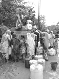 Residents collect their share from a water tanker following severe water shortage in Shivala Mandi near Ambala on Wednesday.