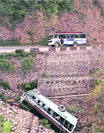 A bus drives past the wreckage of another passenger bus carrying the Amarnath bound pilgrims that skidded off the road, on the outskirts of Jammu