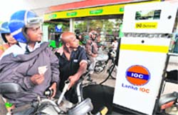 A Sri Lankan petrol pump attendant fills up tank of a motorcyclist at an IndianOil Company petrol station in Colombo