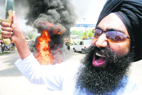 A Sikh brandishes a sword as he shouts slogans during a protest against the Dera Sacha Sauda head in Jammu on Saturday.