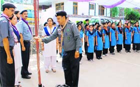 A scout trainer hoisting the flag of the organisation in a private school
