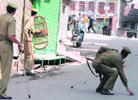 Policeman picks up a stone to disperse demonstators, who protested against the transfer of forest land to Shri Amarnath Shrine Board in Srinagar on Tuesday.