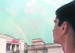 A child looks at the rainbow formed after rainfall in Rajouri.