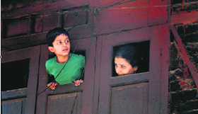 A woman and child watch from a window as members of the newly created Action Committee Against Land Transfer stage a protest in Srinagar on Wednesday.