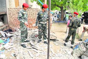 Army men inspect the place outside the kabari shop in Mehna village in Muktsar, where four persons were killed in an explosion