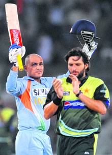 India's Virender Sehwag raises his bat after completing his century as Pakistans Shahid Afridi walks past him during a Group B match at the National Cricket Stadium in Karachi on Thursday.