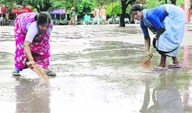 Workers sweep water off the surface near the Sector 17 piazza in Chandigarh.