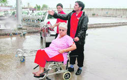An elderly woman being carried on a wheel chair by attendants at the flooded Chandigarh airport.