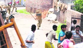 With a lathi in hand, a cop chases protesters who pelted stones on policemen earlier during demonstrations against the revocation of order on forest land in Jammu