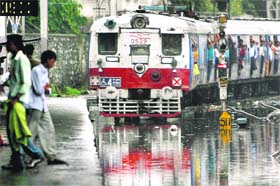 A train travels along a flooded track after heavy rain in Mumbai