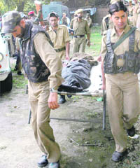 Policemen carry the bodies of a militant and his guard who were killed in a gunbattle with the security forces at Naina Batapora in Pulwama district on Thursday.