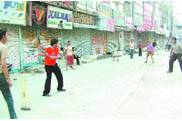 Boys play cricket as shopkeepers down the shutters of their shops on a call for 'Bharat bandh' by the BJP at Rainak Bazaar in Jalandhar