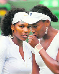 Venus Williams (R) talks to her sister and teammate Serena during their doubles tennis match of the 2008 Wimbledon championships.