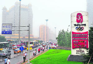 Pedestrians and vehicular traffic pass an Olympic countdown clock in Beijing on Tuesday, one month before the start of the August 8 to 24 summer Olympic Games. 