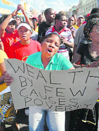 A demonstrator holds a placard during a march to the city hall in Durban on Wednesday. Thousands of South African workers downed tools in protest against a sharp jump in the food and fuel prices, shutting down businesses. 