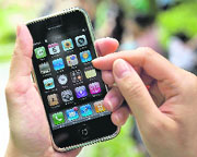 A woman holds up an iPhone handset along a street in Hong Kong.