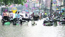 Shopkeepers block heavy traffic by parking their scooters in the middle of the road to prevent water from entering their shop in Ludhiana