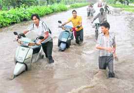 Commuters wade through an inundated road in Panchkula