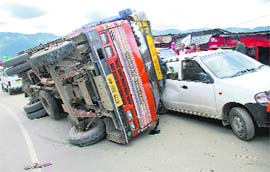 An apple-loaded truck overturns and damages two vehicles at Mehali, near Pantha Gati, in Shimla on Sunday. 
