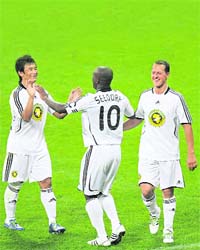 India's Baichung Bhutia, Dutch-Surinamese midfielder Clarence Seedorf and former German Formula One pilot Michael Schumacher celebrate after scoring a goal