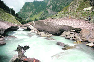 A tourist women enjoys a walk over snow near a rivulet at Chandanwari, 16 km from Pahalgam, where the 32-km-long trek to the holy cave shrine of Amarnath begins. 