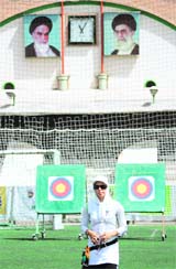 Iranian female archer, Najmeh Abtin who will compete in Beijing Olympics gestures under the portraits of Iranian late and current leaders of the nation during a training session at Tarasht sport complex in Tehran. For the first time in the history of Olympics, three Iranian women will participate at Beijing games in archery, taekwondo and rowing.