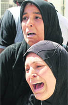 Women wait to claim the body of their relative killed in the attack.