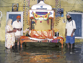 Devotees stand in a knee deep water in a building after heavy rains lashed Ambala on Wednesday.