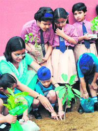 Children along with their teacher plant a sapling during the tree plantation week at Ryan International School in Patiala on Wednesday.