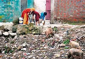 Residents collect water from a tap in an area full of garbage at Rajiv Colony, Panchkula