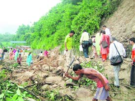 workers labour hard to clear the debris to restore traffic at Kuthma, 15 km from Kangra.