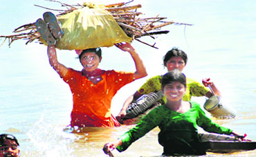 Labourers try to wade through the River Tawi in Jammu