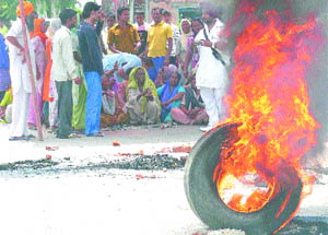 Alleging unfair sarpanch elections, Chuharwali village residents burn tyres and block traffic in Adampur on Friday.