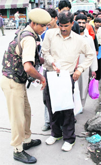 The security has tightened after Saturdays attack on a Army convoy. A security personnel checks the bags of civilians in a market in Srinagar on Sunday.