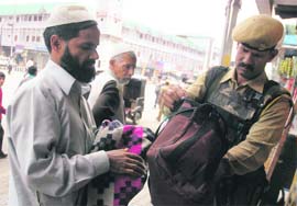 A security personnel checks the bag of a civilian as the security tightened after Saturdays attack on an Army convoy and militants attack on a CRPF patrol party, on the outskirts of Srinagar on Monday.