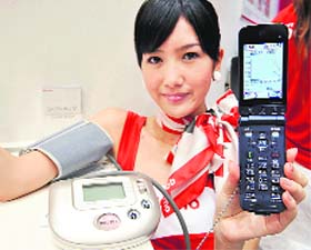An employee of Japanese mobile communication giant NTT docomo displays a new Fujistu "health-care mobile phone" called the "Raku Raku phone V"