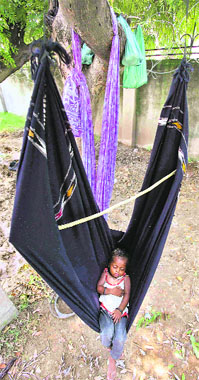 A child sleeps on a makeshift hammock as his mother works at a roadside in Jammu on Tuesday.