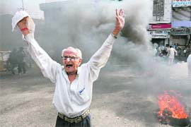 A demonstrator shouts near burning tyres during a protest against the revocation of government order to hand over forest land to Amarnath shrine, in Jammu on Wednesday. 