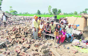 Cong workers watch the demolition of their dwellings at Manjjpur village on the Amritsar-Fatehgarh Churian road on Wednesday.