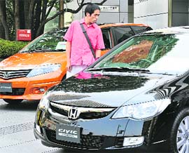 A customer checks Japanese auto giant Honda Motor's vehicles at the company's showroom in Tokyo on Friday. Honda said its net profit rose 8.1 per cent in the three months ending June, but it maintained its forecast for a steep drop in full-year earnings. Net profit hit a record high for the fiscal first quarter at $1.68 billion despite a 2.2 per cent drop in revenue due to a stronger Japanese yen