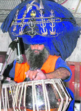 Sant Baldev Singh, wearing 550-metre-long turban weighing 48 kg, plays tabla at Gurdwara Manji Sahib in Ambala on Sunday.