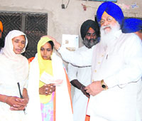 SGPC president Avtar Singh gives a cheque for Rs 5 lakh to the widow of Harminder Singh at her residence in Dabwali on Sunday.
