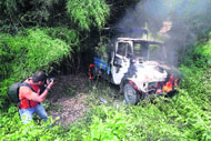 A news photographer takes picture of a police vehicle set on fire during a protest in Jammu on Monday. 