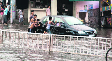 Children push a car stuck in a water-logged street in Ludhiana on Tuesday.