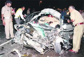 Policemen inspect a car involved in an accident at Rajiv Chowk on the Delhi-Jaipur expressway