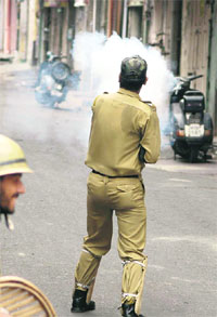 A policeman fires a tear gas shell at agitators in Jammu on Wednesday.