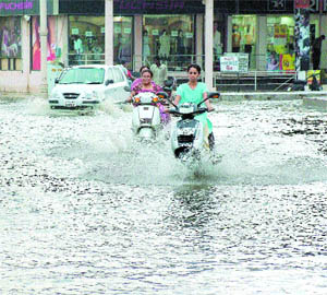 Commuters have a tough time moving through an inundated road in the Model Town area in Jalandhar on Wednesday.