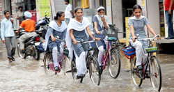 School girls riding bicycles in a waterlogged road following heavy downpour in Mansa on Thursday. The rain, however, brought much-needed respite to the residents from sultry heat