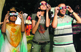 Students watch partial solar eclipse from Nehru Planetarium in New Delhi on Friday.